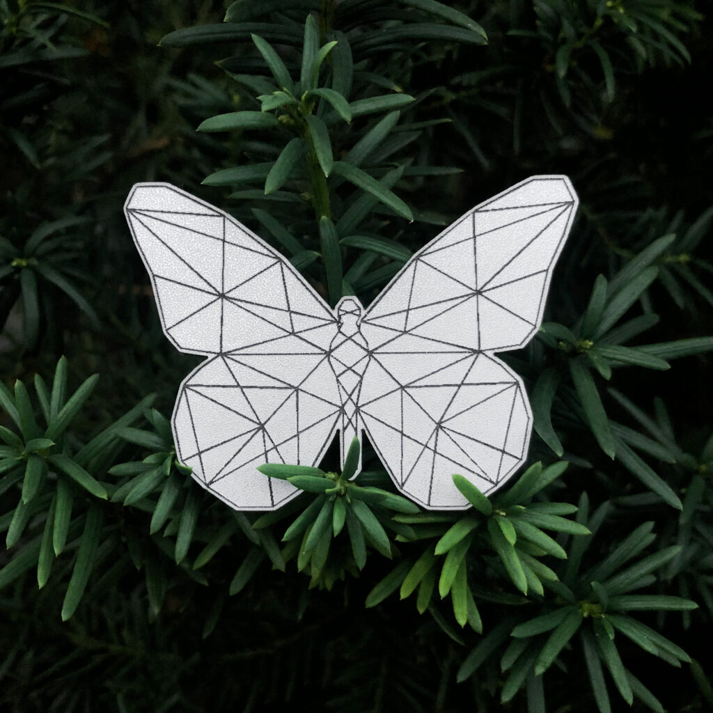 Gray butterfly reflective badge with geometric pattern on a green backround
