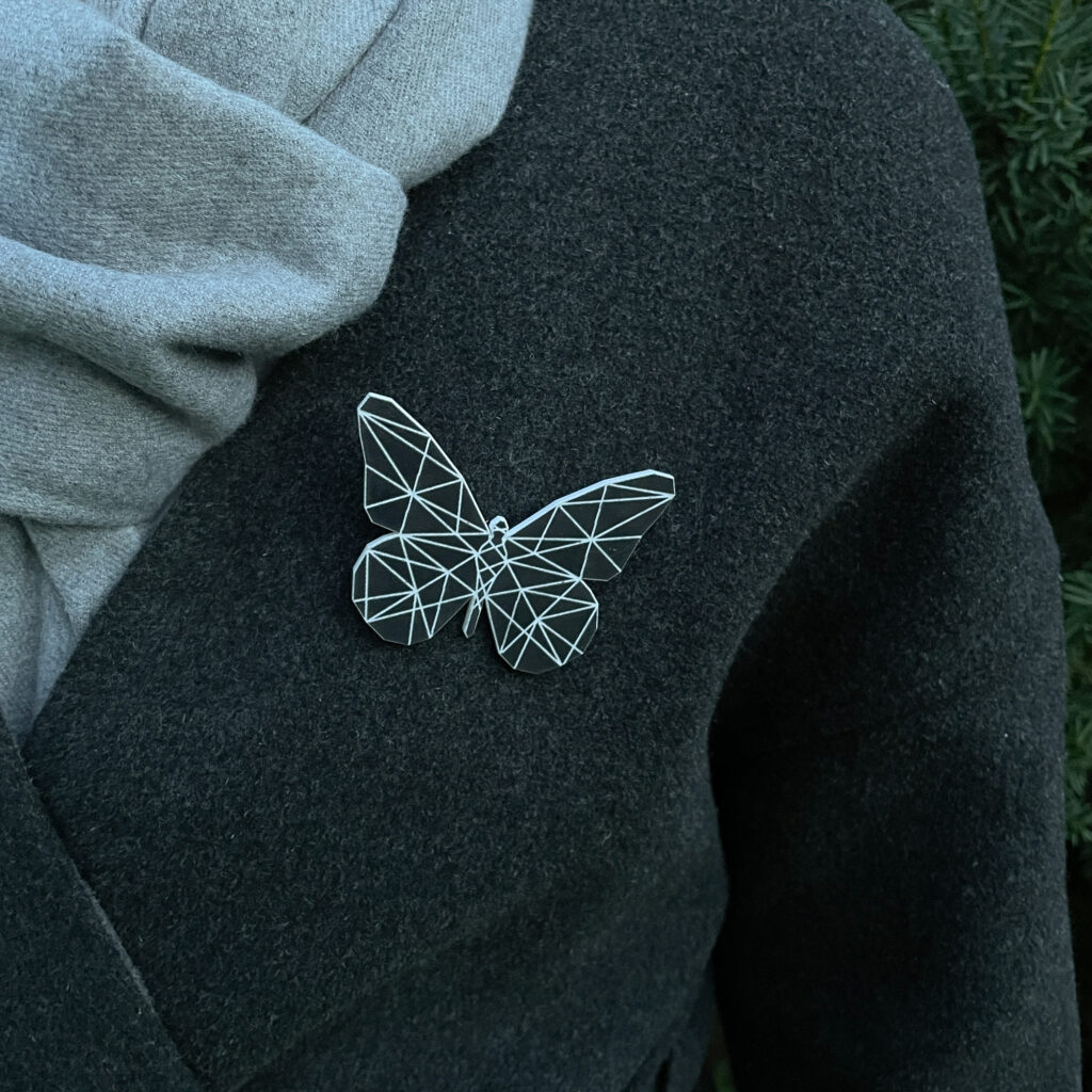 Black butterfly reflecor with geometric pattern on a gray coat